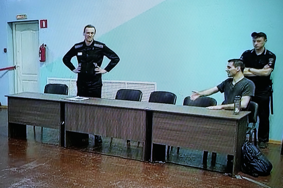 Russian opposition leader Alexei Navalny, left, and his associate Daniel Kholodny are seen at a TV screen as they appear in a video link provided by the Russian Federal Penitentiary Service, during a hearing in the colony, in Melekhovo, Vladimir region, about 260 kilometers (163 miles) northeast of Moscow, Russia, on Friday, Aug. 4, 2023. Navalny on Friday was convicted on extremism charges and sentenced to 19 years in prisons, in the harshest ruling against the imprisoned Kremlin critic to date.