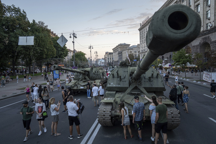 People walk in front of destroyed Russian artillery vehicles installed on Khreschatyk street in downtown of Kyiv, Ukraine, Saturday, Aug. 26, 2023.