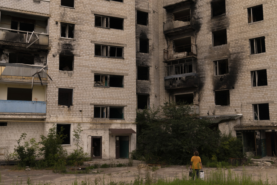 A woman pauses to view an apartment building badly damaged in Russian attacks in Borodyanka, Ukraine, Wednesday, Aug. 2, 2023. Borodyanka was occupied by Russian troops at the beginning of their full-scale invasion last year. (AP Photo/Jae C.