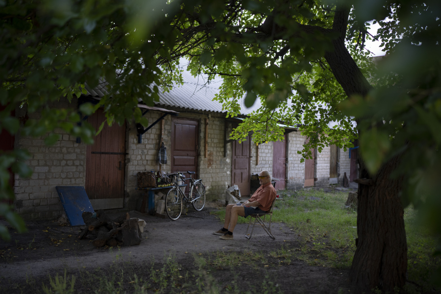 A man sits outside his home in Kupiansk-Vuzlovyi, Ukraine, Wednesday, Aug. 23, 2023. Residents close to the northeast frontline are ignoring calls from Ukrainian authorities to evacuate as the fighting inches closer.