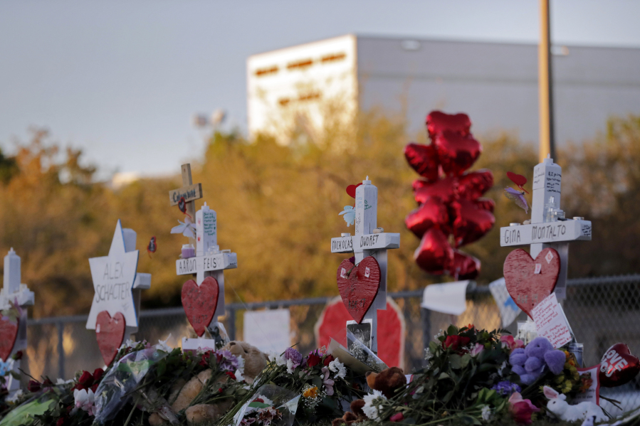 FILE- A memorial is made outside the Marjory Stoneman Douglas High School where 17 students and faculty were killed in a mass shooting in Parkland, Fla, Feb. 19, 2018. The re-enactment of the shooting at the school will take place early Aug. 2023, as part of a civil lawsuit and will use live ammunition.