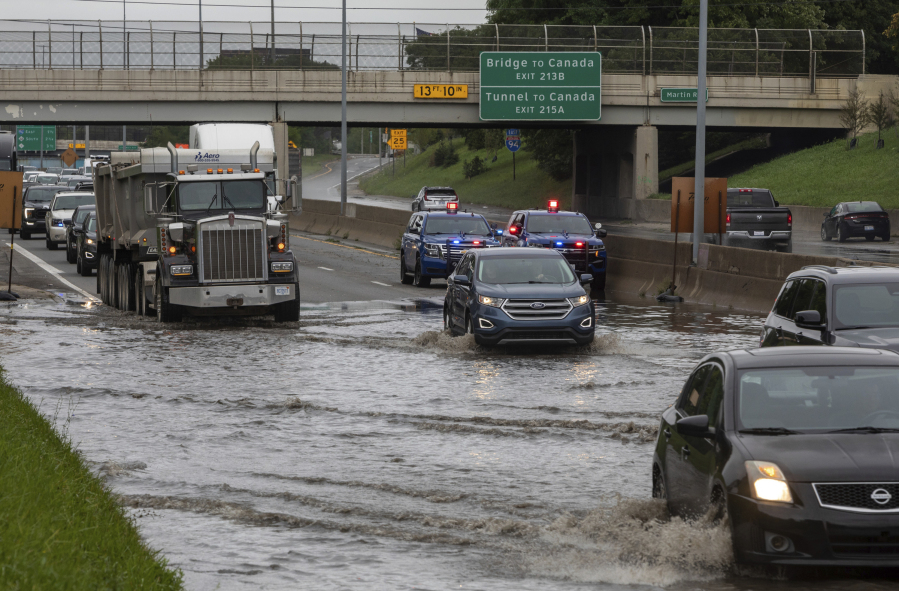 Dozens of vehicles drive through a flooded section of I-94 and Livernois, in Detroit, on Friday, Aug. 25, 2023.