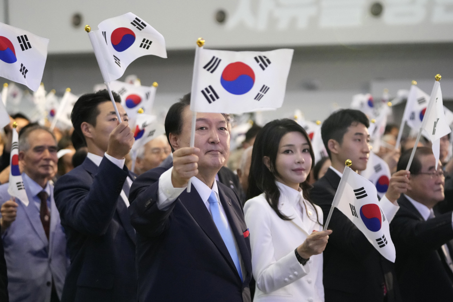 South Korean President Yoon Suk Yeol, center left, and and his wife Kim Keon Hee, center right, wave the national flags during a ceremony to celebrate the 78th anniversary of the Korean Liberation Day from Japanese colonial rule in 1945, in Seoul, South Korea, Tuesday, Aug. 15, 2023.