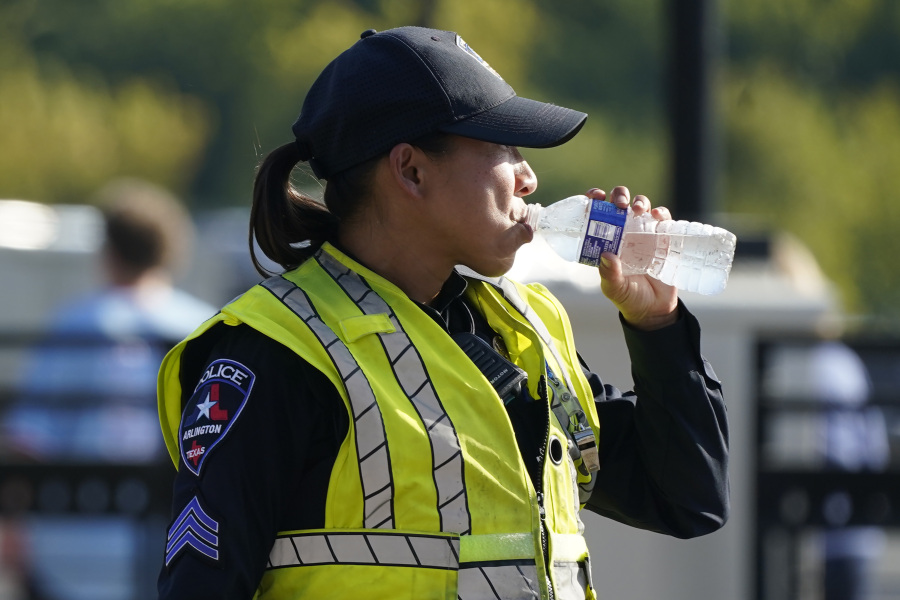 A police officer directing traffic takes a break to drink water after a sporting event in Arlington, Texas, Saturday, Aug. 19, 2023. The summer of 2023 may be drawing to a close -- but the extreme heat is not: More record-shattering temperatures -- this time across Texas -- are expected Saturday and Sunday as the U.S. continues to bake.