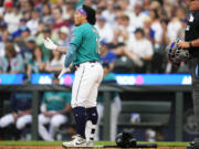 Seattle Mariners' Kolten Wong removes his batting gear after striking out swinging against the Detroit Tigers to end the third inning of a baseball game Saturday, July 15, 2023, in Seattle.
