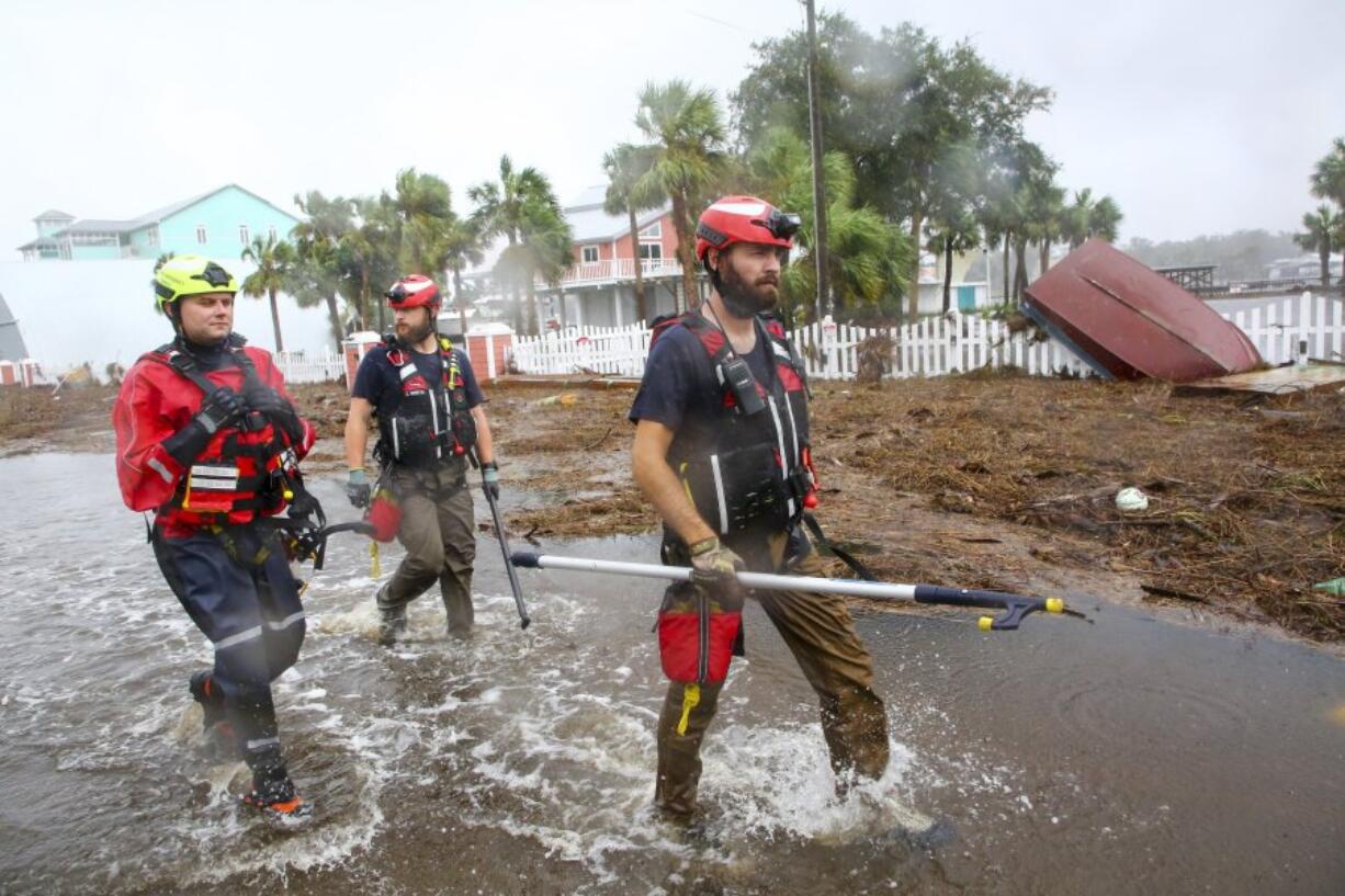 Rescue workers with Tidewater Disaster Response, from left, Zack Hoeth, Zack McCue, and Mike Foster, of Fairfax, Va., search SW 358 Highway for people in need of help Wednesday, Aug. 30, 2023, after the arrival of Hurricane Idalia. (Douglas R.