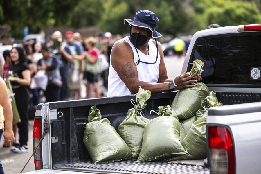 Ronald Thompkins, 60, loads sandbags onto a truck in preparation for the arrival of Hurricane Hilary in San Bernardino, Ca., on Saturday, Aug. 19, 2023, while residents queue at Wildwood Park to fill sandbags for the impending storm.