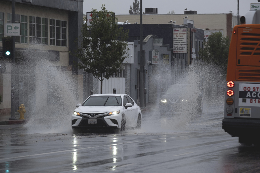 A vehicle splashes through puddles along a street starting to flood in the Van Nuys section of Los Angeles as a tropical storm moves into the area on Sunday, Aug. 20, 2023. Tropical Storm Hilary is no longer a hurricane but it's still packing what forecasters call "life-threatening" rain as it speeds up Mexico's Baja coast toward Southern California.