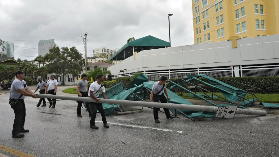 Members of the Tampa Fire Rescue Dept., remove a street pole after large awnings from an apartment building blew off from winds associated with Hurricane Idalia Wednesday, Aug. 30, 2023, in Tampa, Fla. Idalia made landfall earlier this morning along the Big Bend of the state.