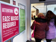 A sign announcing a face mask requirement is displayed at a hospital in Buffalo Grove, Ill., Friday, Jan. 13, 2023. COVID-19 hospital admissions are inching upward in the United States since early July 2023. It's a small-scale echo of the three previous summers. (AP Photo/Nam Y.