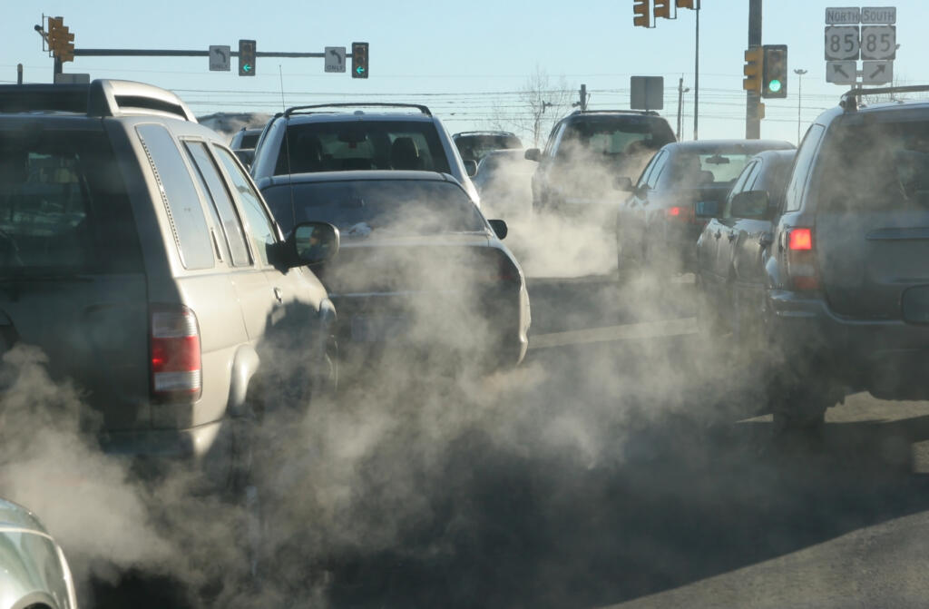 At an intersection in Denver, exhaust pours out of a tailpipes from vehicles.