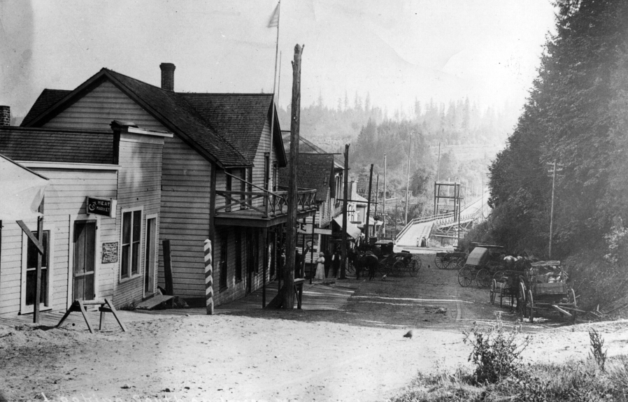 This photo of La Center before the 1907 fire that burned most of the town's businesses shows the bridge the safecrackers noisily crossed in the background. They came up the road and entered the village, attempting to crack two safes, one in a saloon and the other in a store. Instead, they started a fire that burned out the town. As they left they dropped a half-full liquor bottle on the bridge. They were never caught. The sole business left standing was a blacksmith shop.