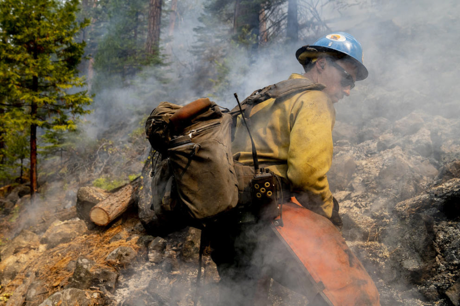 Blue Ridge Hot Shots cut trees and dig a fireline on a steep-sloped mountain to suppress the Dixie Fire in Lassen National Forest, California, in September 2021.