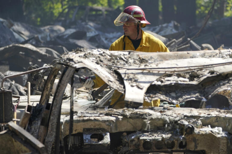 A firefighter looks for hotspots, Tuesday, Sept. 8, 2020, after a wildfire destroyed homes and outbuildings in Graham, Wash., overnight south of Seattle. (AP Photo/Ted S.