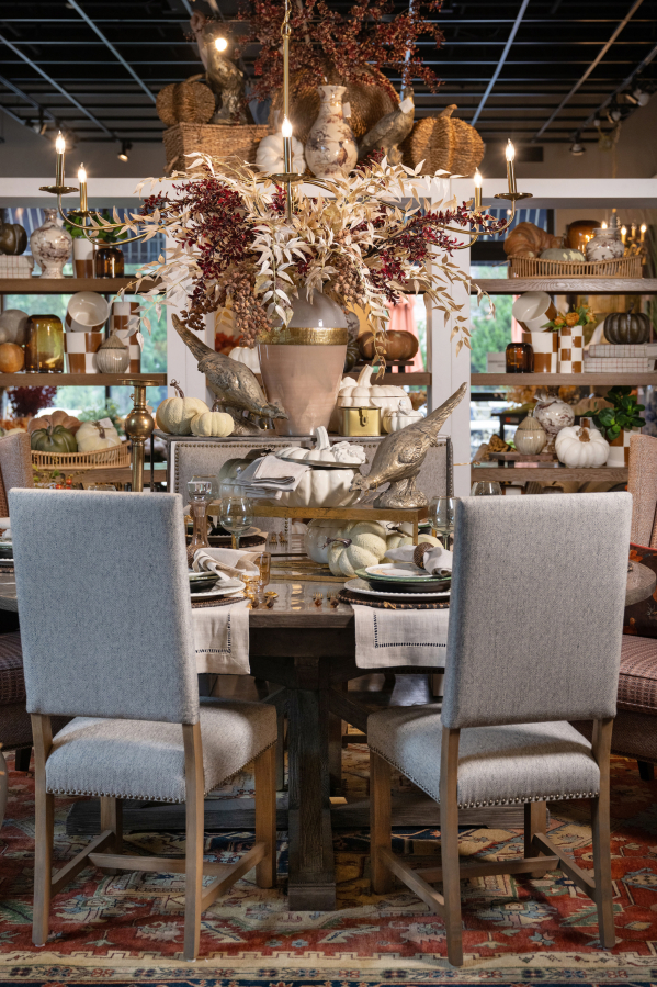 An elegant table is set with beautiful neutral tones, flanked by sleek gray dining chairs.