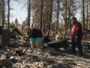 Jennie Tinsley and partner Jacob Bouvette look through the rubble of their home that burned down in the Gray Fire on Aug. 31, 2023.