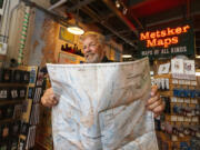 Alan Coburn, president of Green Trails Maps, holds a new revised edition of the Mount Rainier map at Metsker Maps in Seattle. The map company is turning 50 and Metsker was the first retailer to carry them.