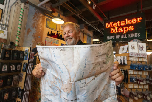 Alan Coburn, president of Green Trails Maps, holds a new revised edition of the Mount Rainier map at Metsker Maps in Seattle. The map company is turning 50 and Metsker was the first retailer to carry them.