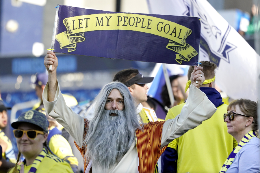 Stephen Mason, dressed as "Soccer Moses," holds up a sign which reads, "Let my people goal" before an MLS soccer match between Nashville SC and New York Red Bulls Sunday, Nov. 7, 2021, in Nashville, Tenn. His face flies on a flag outside the Nashville new stadium and he's often found in the team's supporter section, where its most devoted fans gather.