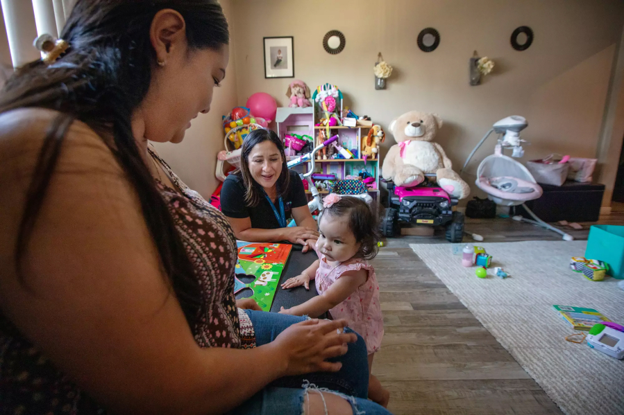 Parent coach Alba Mariscal, center, visits Ilse Ochoa and her 10-month-old daughter, Brianna de Leon, in Compton, Calif. Parent coaches go house to house, checking in on families through the first year of their baby's life, offering tips, advice and support.
