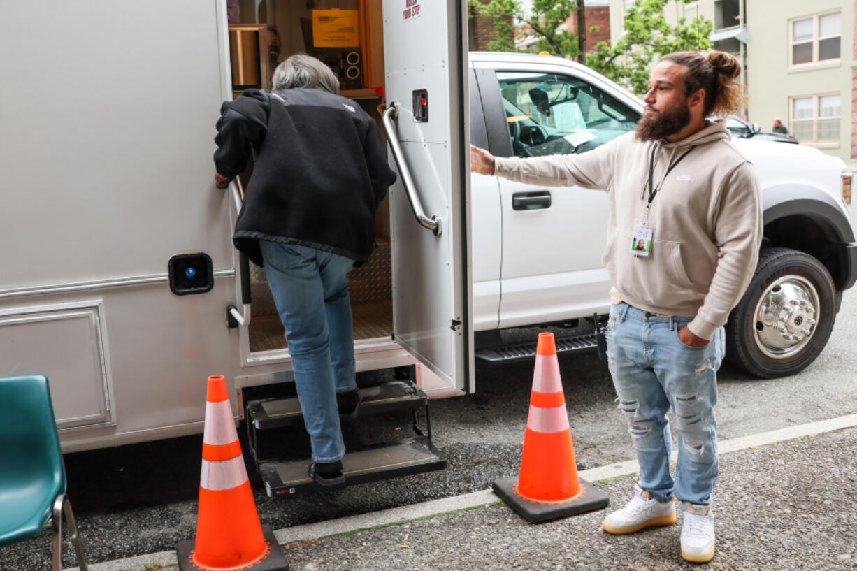 Brendan Medbury, hospitality and engagement worker with Evergreen Treatment Services, holds the door for a client Friday morning in the Belltown neighborhood of Seattle, on Aug. 18, 2023.