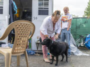 Martha Petifer, left, puts a leash on her dog, Odyssey, while her partner Clint Austin watches at The Outpost Safe Stay Community, where she has lived since February. Petifer suffered a stroke and broken back in January.