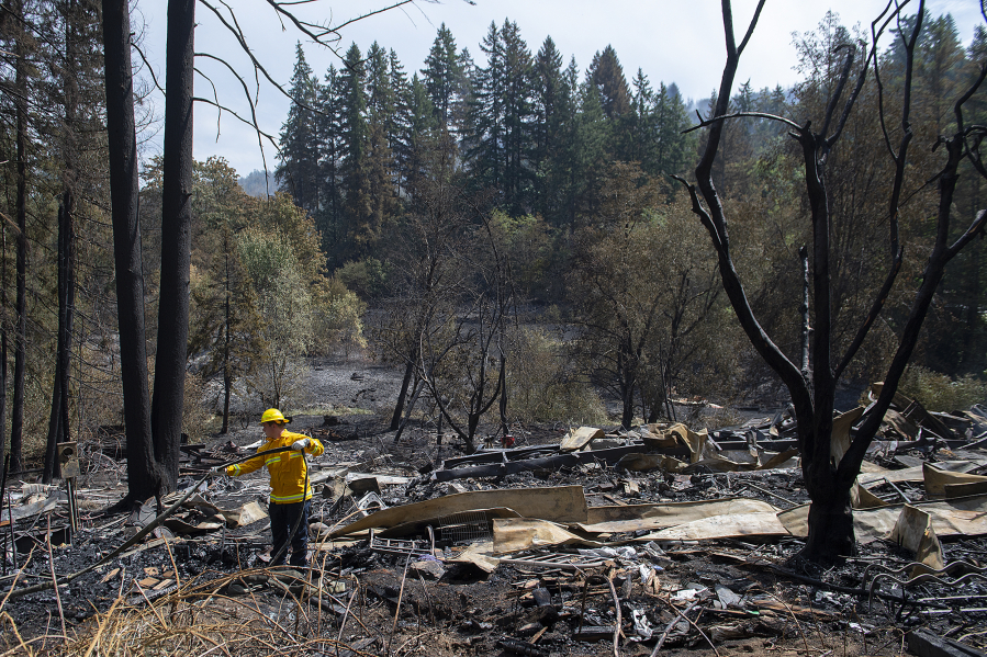 Firefighter Michael Hickey works at the scene on Aug. 17 after a blaze destroyed a house and surrounding structures on the same property near La Center. The incident sparked a significant brush fire that prompted evacuation warnings. well into the north county community.