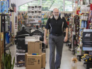 Nick Crawford, co-owner of Hi-School Hardware, walks the aisle with shop dog, Boo Boo, while working in Uptown Village.