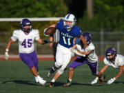 Mountain View's Aiden Nicholson (11) evades tackles from Nooksack Valley defenders in the season-opening football game Friday at McKenzie Stadium.