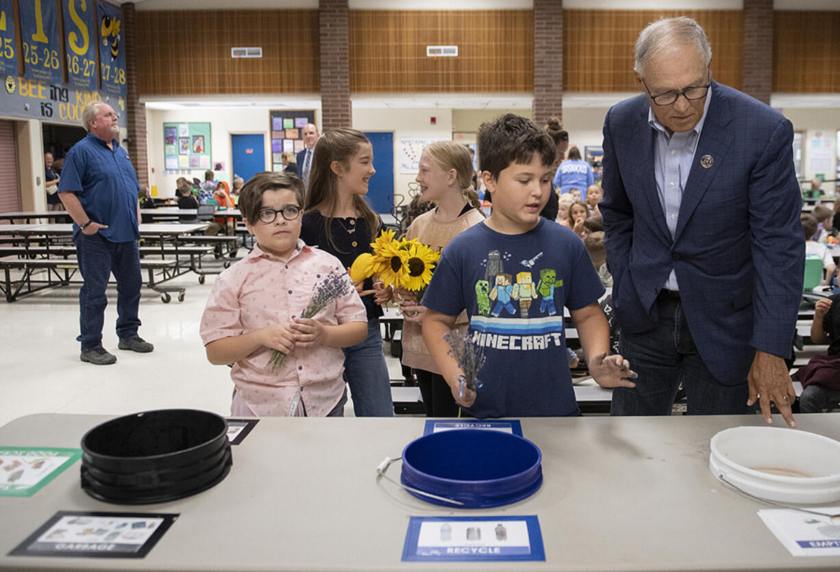 Hockinson Heights Elementary School fifth graders Kevin Brown, with sunflowers from left, Perry Burnham, Charlie O'Donnell Munson-Young, and Bear Ricks, all 10, show Gov. Jay Inslee the recycling area in their cafeteria as he toured their school.