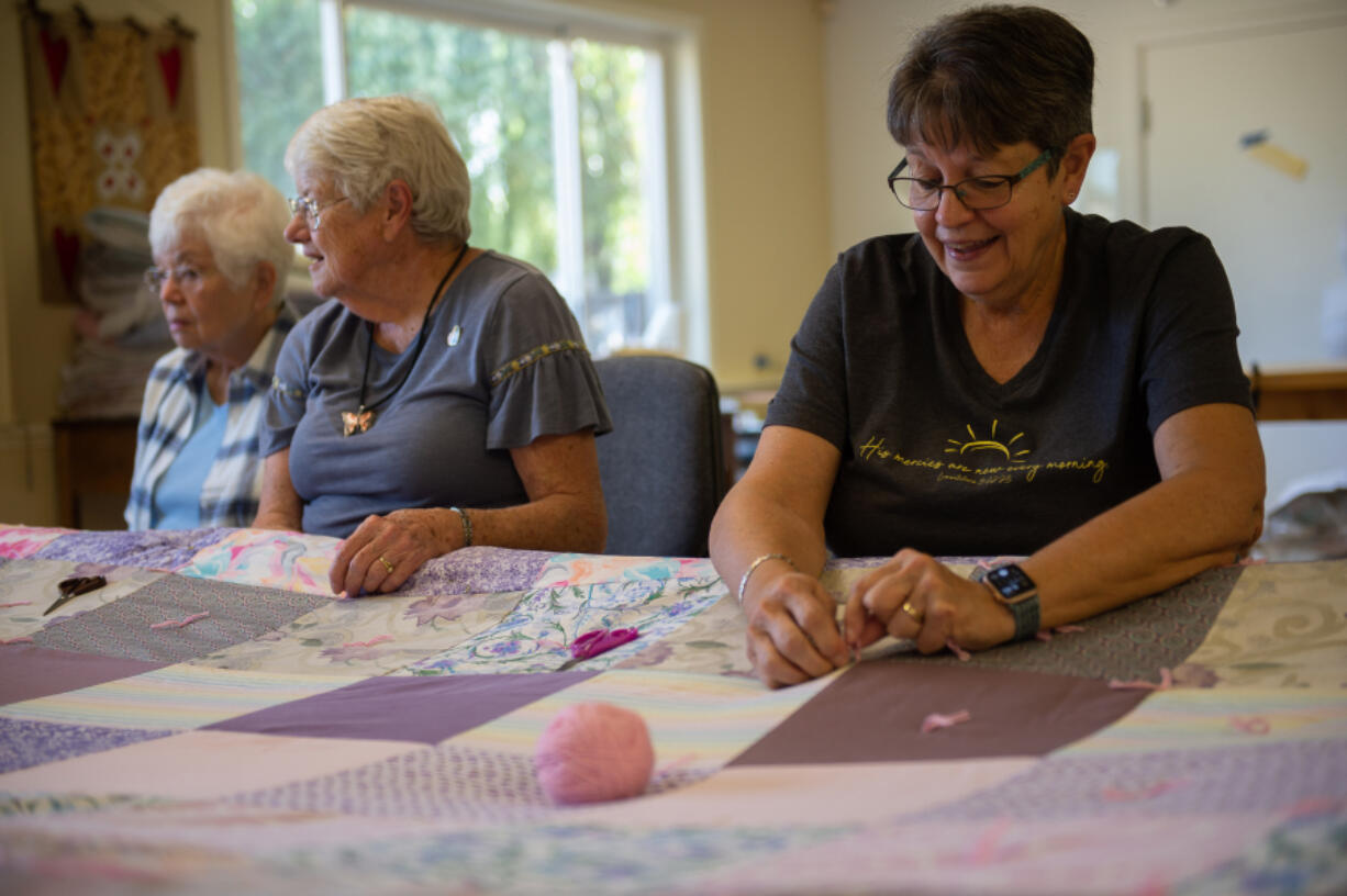 Carol Burbridge, Judy Blevens and Joyce Harms work on a quilt in a back room at St. Andrew Lutheran Church in Vancouver.