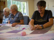 Carol Burbridge, Judy Blevens and Joyce Harms work on a quilt in a back room at St. Andrew Lutheran Church in Vancouver.