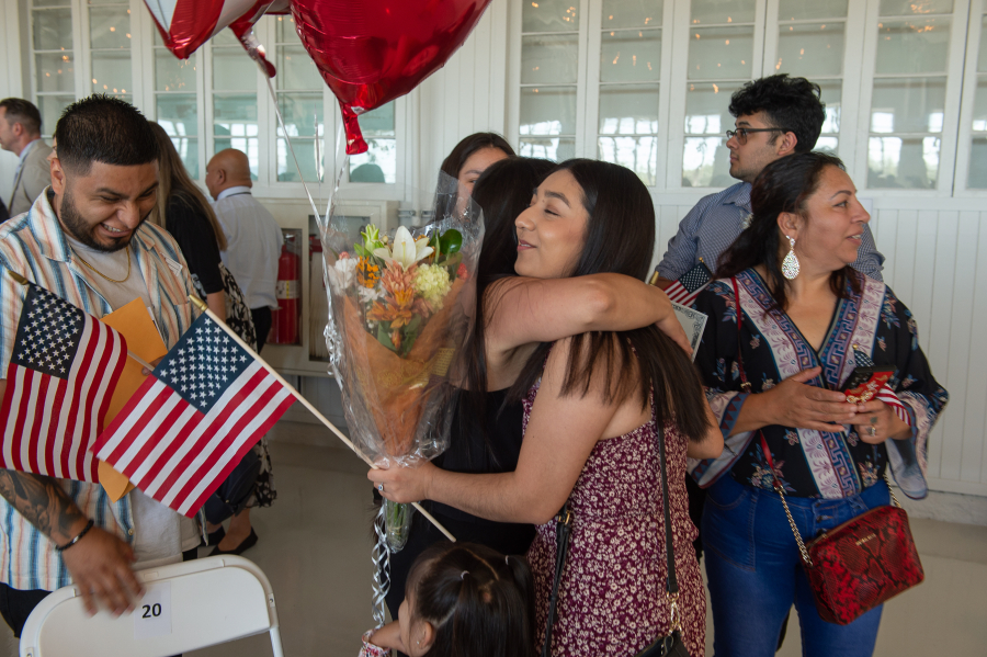 Bibiana Pinon-Hernandez is hugged by family Thursday morning after becoming a naturalized U.S. citizen after emigrating from Mexico. At top, Maria Miramon, from Mexico, also becomes a U.S. citizen during a ceremony at the Pearson Air Museum Hangar.