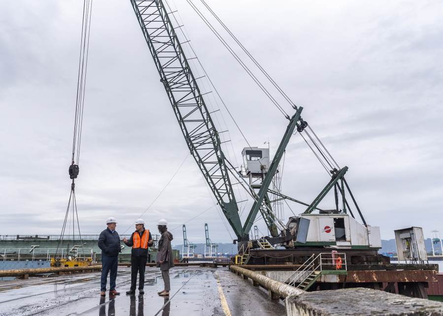 Rep. Marie Gluesenkamp Perez, D-Skamania, and White House senior adviser Mitch Landrieu, right, tour Tidewater Barge Lines' dock with CEO Todd Busch. Tidewater won a federal infrastructure grant to replace an old diesel-powered crane, seen at right, with a new electric model.