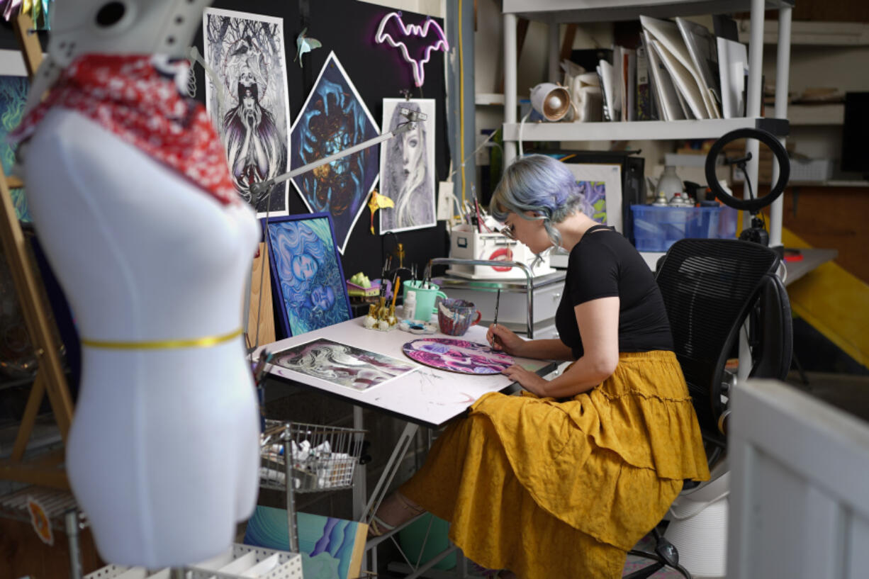 Artist Kelly McKernan paints in their studio Tuesday, Aug. 15, 2023, in Nashville, Tenn. McKernan is an artist and one of three plaintiffs in a lawsuit against artificial intelligence companies they allege have infringed on their copyright.