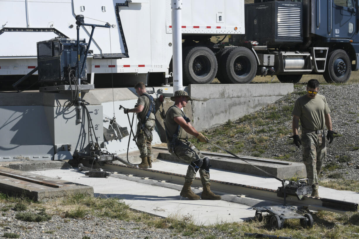 In this image provided by the U.S. Air Force, Airman 1st Class Jonathan Marrs, 21, left, and Senior Airman Jacob Deas, 23, right, work to dislodge the 110-ton cement and steel blast door covering the top of the Bravo-9 nuclear missile silo at Malmstrom Air Force Base, Mont., Aug. 24, 2023. When the first 225-pound aluminum tow, or "mule" could not pull the door open, Marrs dragged down a second tow to give them more power. (John Turner/U.S.