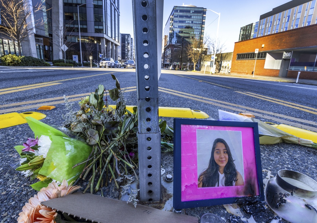 A photo of Jaahnavi Kandula is displayed with flowers, Sunday, Jan. 29, 2023 in Seattle, at the intersection where she was killed by a Seattle Police officer driving north while responding to a nearby medical incident. A city watchdog agency is investigating after a body-worn camera captured one Seattle Police Department union leader joking with another following the death of a Kandula, who was struck and killed by a police cruiser as she was crossing a street.