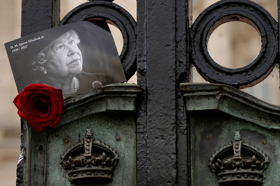 A tribute to Britain's Queen Elizabeth II, is tucked into the gates of Buckingham Palace in London, Friday, Sept. 8, 2023. With gun salutes and tolling bells, Britain is marking the first anniversary of the death of Queen Elizabeth II and the ascension of King Charles III, who remembered his mother as a symbol of stability during her 70-year reign.