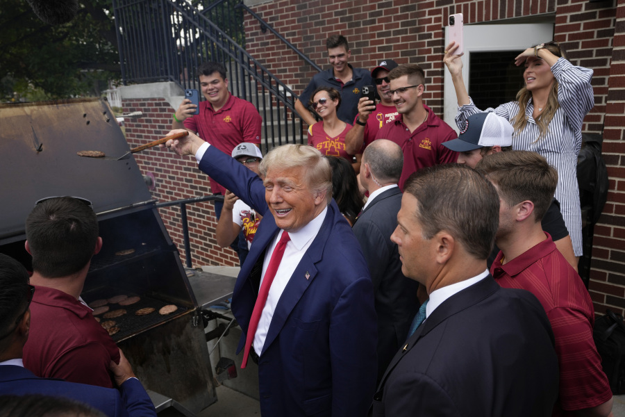 Former President Donald Trump holds a spatula with a hamburger on it as he works the grill during a stop at the Alpha Gamma Rho, agricultural fraternity, at Iowa State University before an NCAA college football game between Iowa State and Iowa, Saturday, Sept. 9, 2023, in Ames, Iowa.