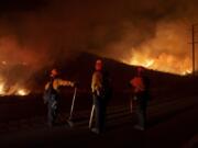 FILE - Firefighters monitor as flames consume brush along Gilman Springs Road during the Rabbit Fire, July 14, 2023, in Moreno Valley, Calif. More Americans believe they've personally felt the impact of climate change because of recent extreme weather according to new polling from The Associated Press-NORC Center for Public Affairs Research.
