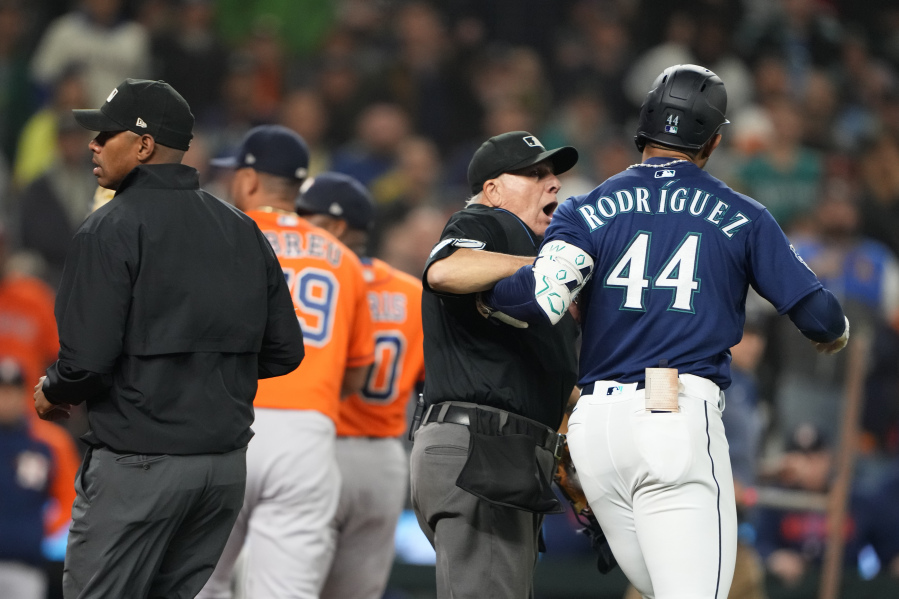 Seattle Mariners' Julio Rodriguez (44) is held back by an umpire after he exchanged words with Houston Astros relief pitcher Hector Neris following a strikeout in a baseball game Wednesday, Sept. 27, 2023, in Seattle. The Astros won 8-3.