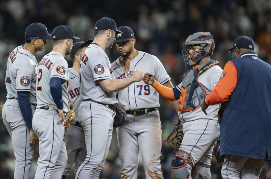 Houston Astros starting pitcher Justin Verlander gets a fist bump from catcher Marten Maldonado, second from right, before getting pulled by manager Dusty Baker, far right, in a meeting at the mound with shortstop Jeremy Pena, far left, third baseman Alex Bregman, second from left, and first baseman Jose Abreu (79) in the ninth inning of a baseball game against the Seattle Mariners, Monday, Sept. 25, 2023, in Seattle. The Astros won 5-1.