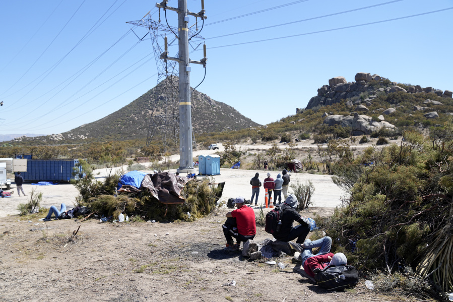 Asylum-seekers wait in a makeshift camp after crossing the nearby border with Mexico, Wednesday, Sept. 20, 2023, near Jacumba Hot Springs, Calif. Migrants continue to arrive to desert campsites along California's border with Mexico, as they await processing in tents made from tree branches.