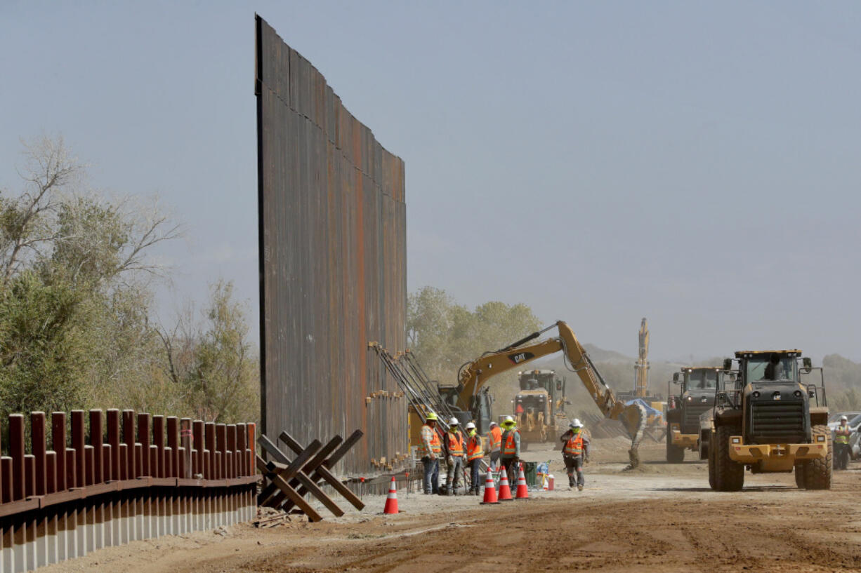 FILE - Government contractors erect a section of the Pentagon-funded border wall along the Colorado River, Sept. 10, 2019, in Yuma, Ariz. Construction of the wall along the U.S.-Mexico border under former President Donald Trump toppled untold numbers of saguaro cactuses in Arizona, put endangered ocelots at risk in Texas and disturbed Native American burial grounds, Congress' official watchdog said Thursday, Sept. 7, 2023.