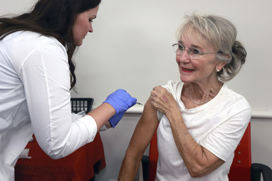 CVS pharmacist Katie Gilmore administers vaccinations for COVID-19 and seasonal flu to Baldwin Park resident Angie Chandler at the store Friday in Orlando, Fla. Pharmacies across the U.S. have started administering new COVID-19 boosters.