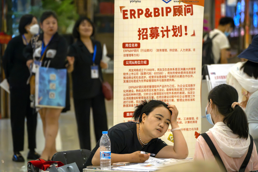FILE - A recruiter talks with an applicant at a booth at a job fair at a shopping center in Beijing, on June 9, 2023. A record of more than one in five young Chinese are out of work, their career ambitions at least temporarily derailed by a depressed job market as the economy struggles to regain momentum after its long bout with COVID-19.