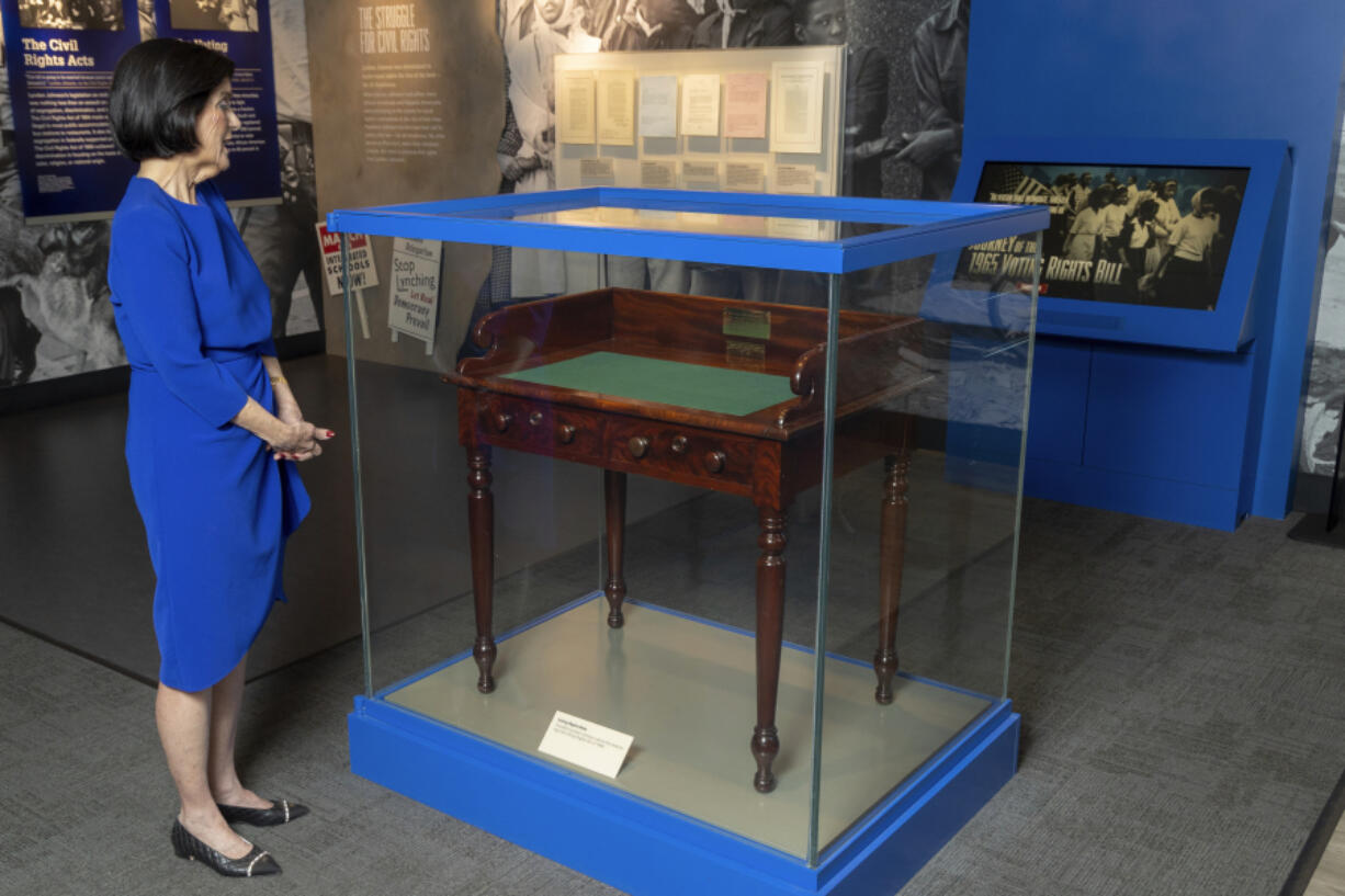 FILE - Luci Baines Johnson looks at the desk on May 16, 2023, on display at the LBJ Presidential Library, that President Lyndon B. Johnson sat at in the President's Room at the U.S. Capitol to sign the Voting Rights Act of 1965, on Aug. 6, 1965. Concern for U.S. democracy amid deep national polarization has prompted the entities supporting 13 presidential libraries dating back to Herbert Hoover to call for a recommitment to the country's bedrock principles, including the rule of law and respecting a diversity of beliefs.