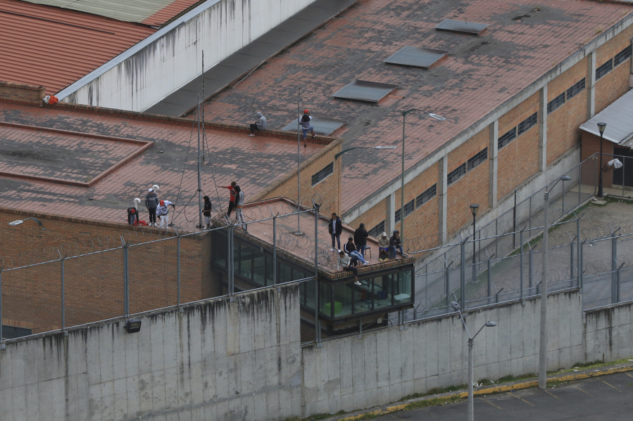 Prisoners stand on the roof of the Turi jail where dozens of prison guards and police officers have been kidnapped by the inmates, in Cuenca, Ecuador, Thursday, Aug. 31, 2023. In the last 24 hours, Ecuador has been rocked by the explosions of four car bombs and the hostage-taking of more than 50 law enforcement officers inside various detention facilities.