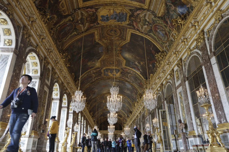 FILE - Visitors walk inside the Hall of Mirrors in the Versailles castle, on Nov. 17, 2015 in Versailles, west of Paris. France is rolling out the red carpet for King Charles III's state visit starting on Wednesday Sept. 20, 2023 at one of its most magnificent and emblematic monuments: the Palace of Versailles, which celebrates its 400th anniversary.
