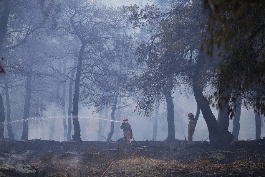 Firefighters spray water inside a woodland during a wildlife in the suburb of Stamata, in northern Athens, Greece, Monday, Sept. 4, 2023. Wildfires are common in Greece and other southern European countries during their hot, dry summers as dozens of fires have been breaking out each day across the country for weeks.